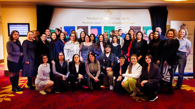 A group of people standing together in a conference room with a carpeted floor and colorful banners in the background.